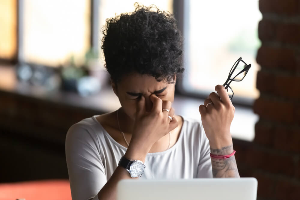 African American woman taking off glasses, feel eye strain, massaging nose bridge, tired female feeling discomfort after long wearing glasses at workplace, work with computer, bad eye vision close up