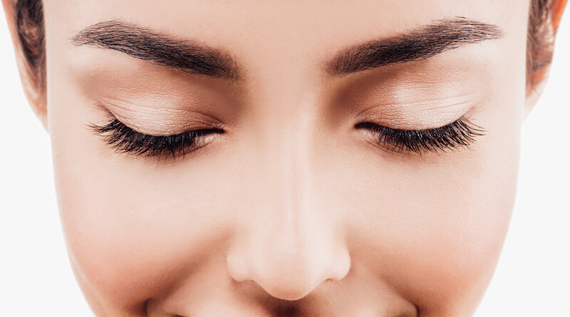 Woman with very full eye lashes. Her eyes are closed.